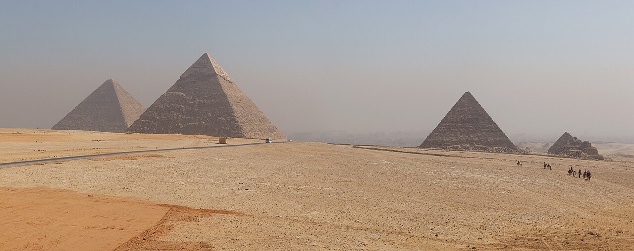 جولة فاخرة في الأهرامات الكبرى في الجيزة، مصر، وتتميز بالهرم الأكبر لخمعبا، خفرع، ومنكاورع تحت سماء صحراوية غائمة. | Luxury tour of the Great Pyramids of Giza, Egypt, featuring the Great Pyramid of Khufu, Khafre, and Menkauser under a hazy desert sky.
